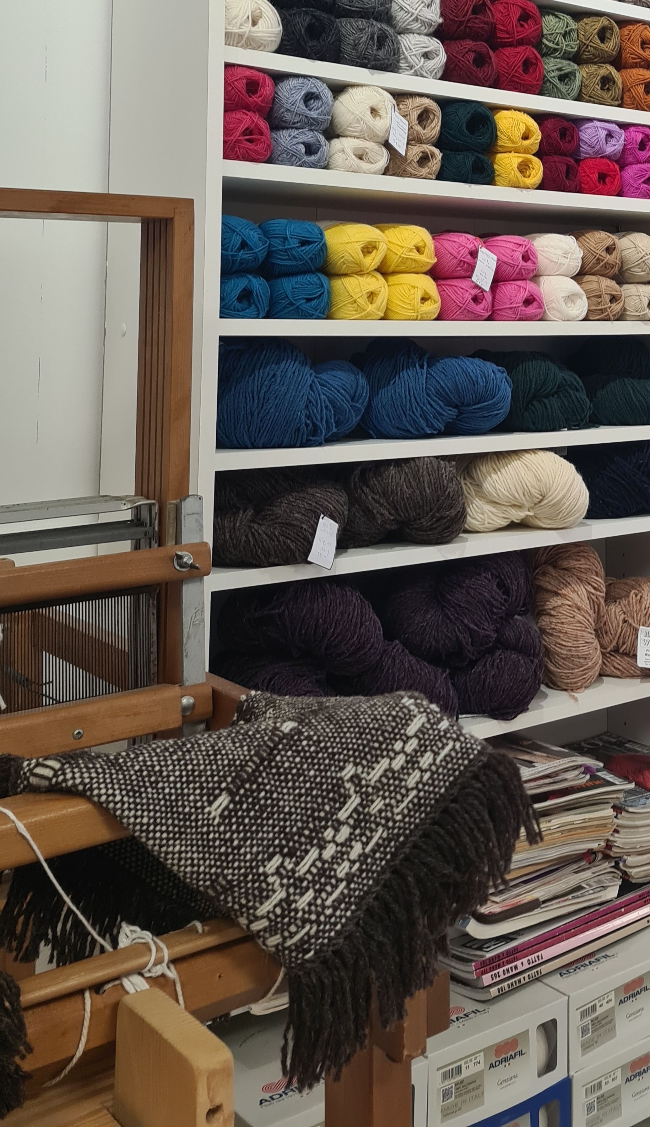 Un métier à tisser avec un travail bariolé en cours et des vètements tricotés à côté